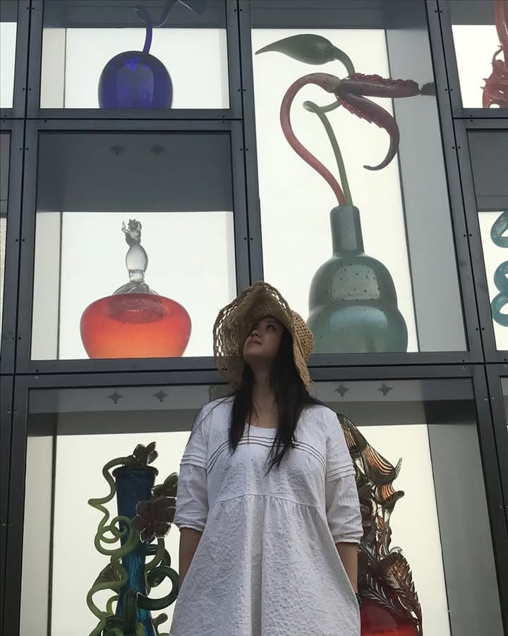 Portrait of Rosa standing in front of large glass art displays.